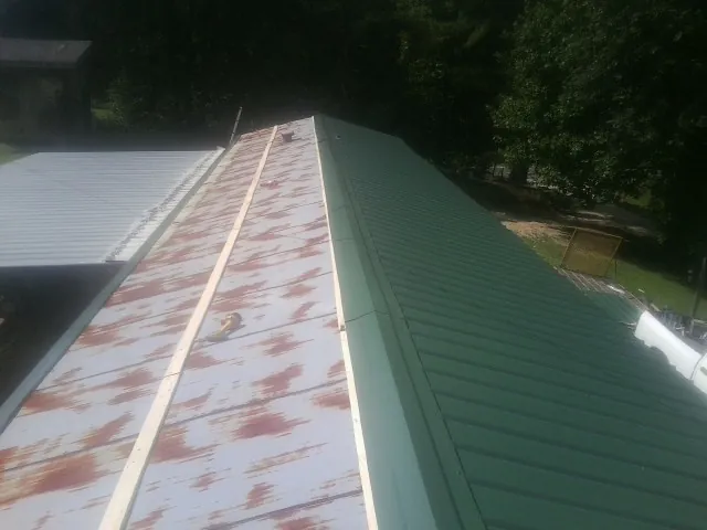 Old rusted panels beside newly installed green metal roofing — Wind Damage Roof Repair by Roofing Brothers in Franklinville