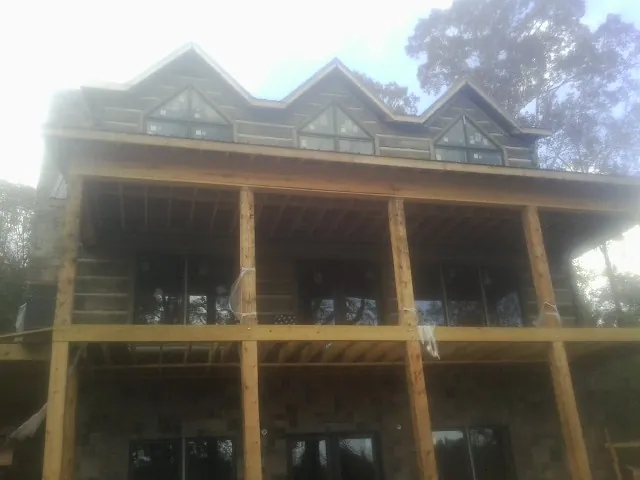 Dormers and porch framing on a large log home under construction — Roof Coating work by our crew in Franklinville