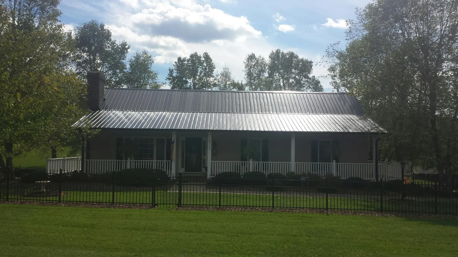 Gray metal roof on a brick ranch with a full width front porch — Gutter Guard Installation work by our crew in Franklinville