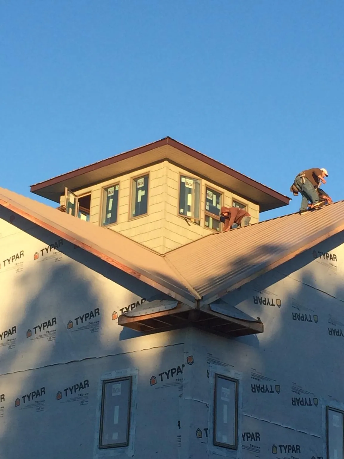 Roofers working around a rooftop cupola on a new metal roof at sunset — Roof Waterproofing in Franklinville by Roofing Brothers